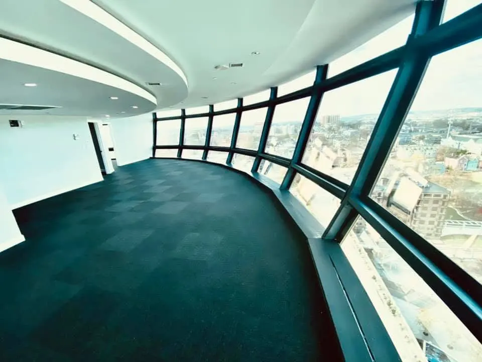 Curved high-rise office overlook with green commercial carpet and floor-to-ceiling windows